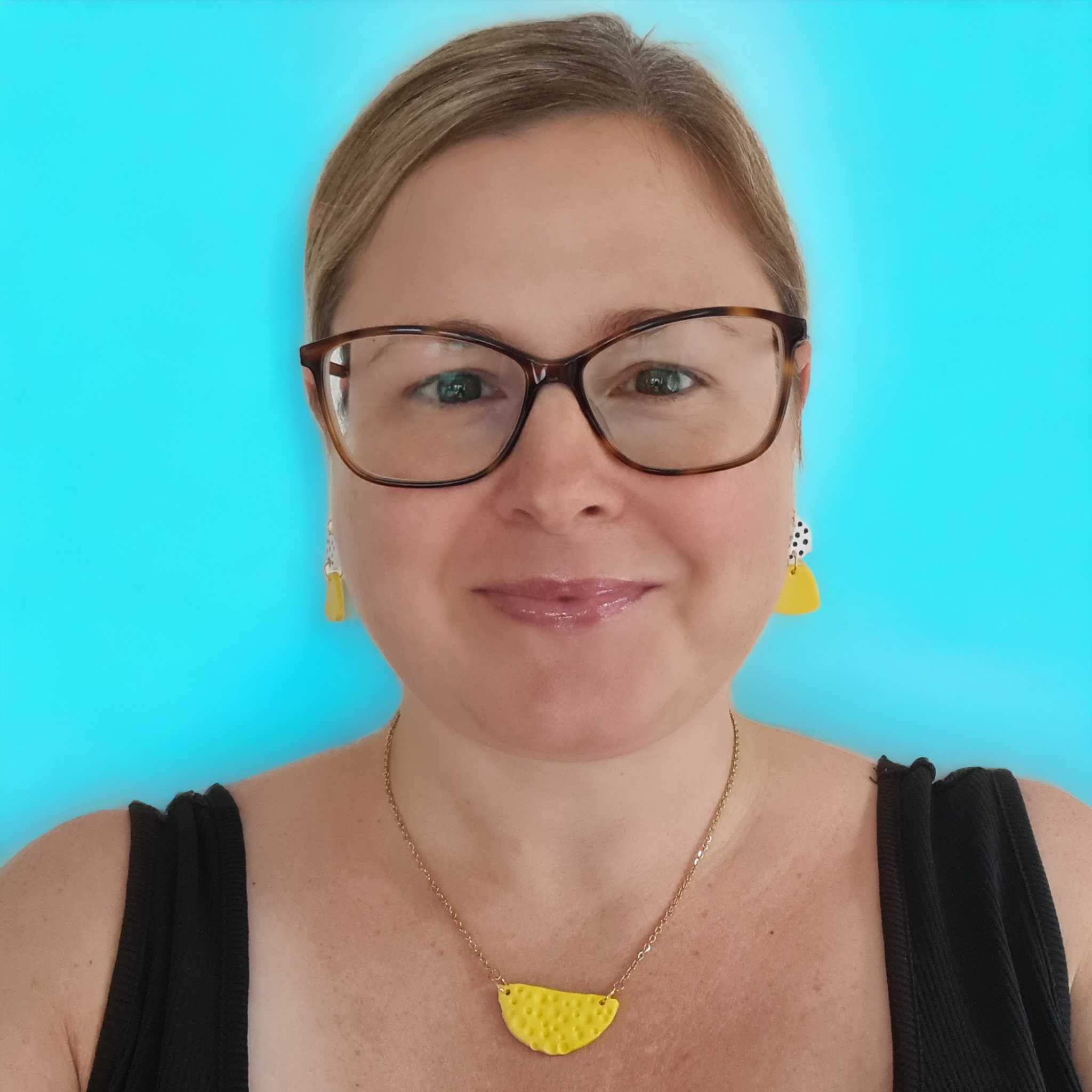 A photo of Amy Ayton wearing a pair of yellow earrings and a black top.